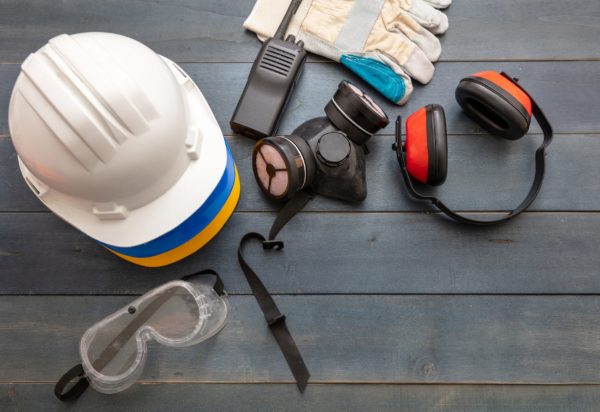 Work safety protection equipment flat lay. Industrial protective gear on blue wooden background. Construction site health and safety concept, copy space.