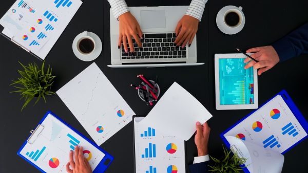 Top view of creative professional business people brainstorming innovative ideas for startup company viewing market research statistics using tablet in boardroom meeting. Copy space, flat lay concept